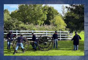 A group of 6 men in Civil War blue uniforms preparing a cannon for firing. 