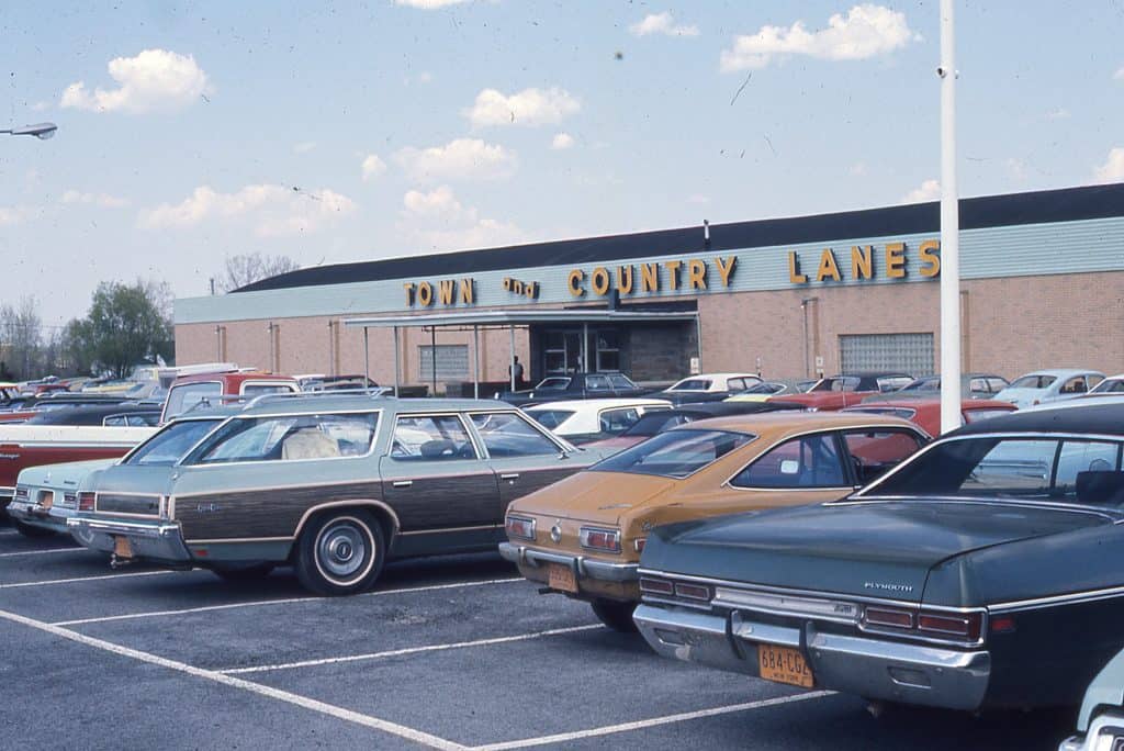 Cars from the 1970s parked in the lot of Town and Country Lanes bowling lanes.
