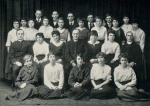 A class of young people, mostly girls, posed with three young priests.