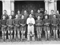 Men with lacrosse sticks in front of a building