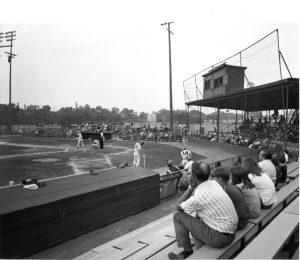 People sitting in the stands of Shuron Park watching a baseball game.