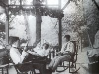 three people sitting on cottage porch early 1900s