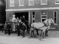 Horse drawn fire wagon in front of a building