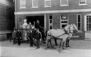 Horse drawn fire wagon in front of a building