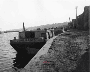 A small boat with a cabin docked alongside a seawall.