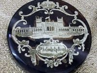 black button with silver image of building 1876
