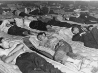 Men sleeping on mattresses in the Dove Block during World War II