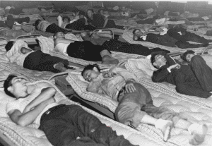 Men sleeping on mattresses in the Dove Block during World War II
