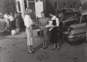 Two femal students standing outside a building with an adult